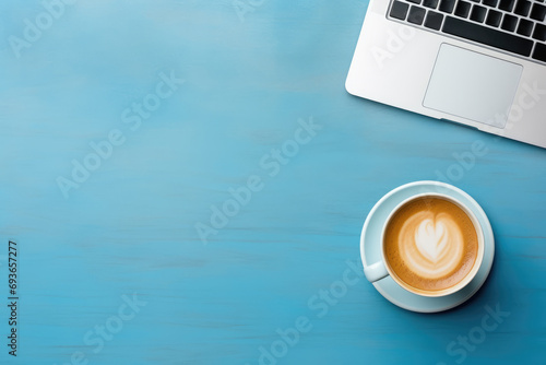 top view of a minimalist workspace featuring a sleek laptop and a cup of coffee on a vibrant blue background, with free space for text or advertising