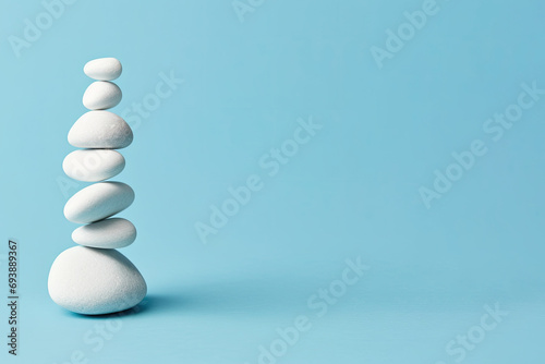  White sea pebble stone stack on light blue background. stack of zen stones on blue . copy space for text