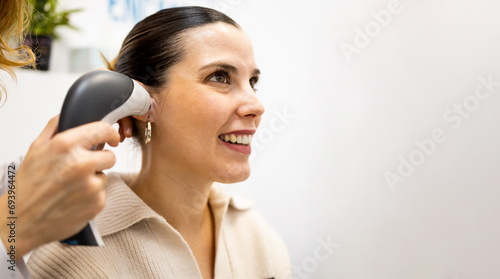 An unrecognizable female doctor uses otoscope to check the ear of a girl patient. Otoscopy and hearing check for people with hearing problems in audiology or hearing clinic.