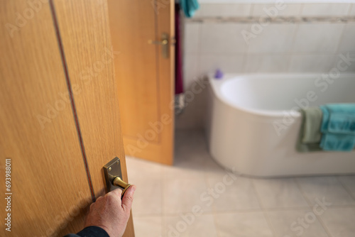 Shallow focus of a home owner seen entering a newly fitted, modern bathroom which features twin doors to separate bedrooms.