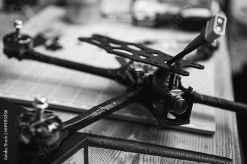 black and white photo, Frame, FPV racing drone frame, assembly, soldering, for the armed forces of Ukraine, installed with tools on the desktop, close-up view