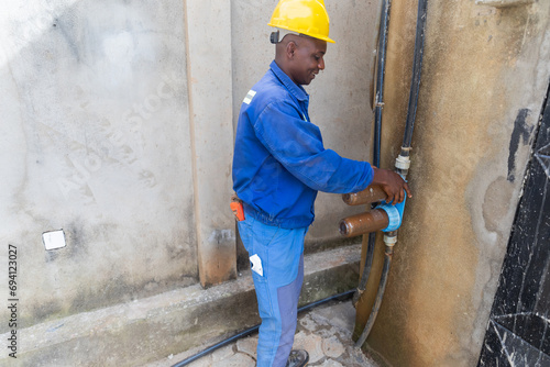 An African blue collar worker preparing to replace dirty rusty water filters