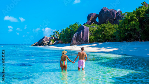 Anse Source d'Argent beach La Digue Island Seychelles, a couple of men and woman walking at the beach at a luxury vacation. a couple swimming in the turqouse colored ocean