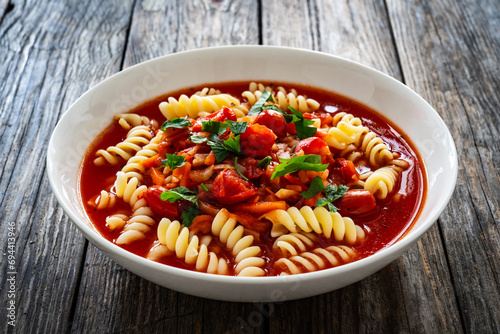 Tomato soup with noodles on wooden table 