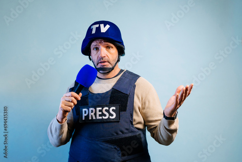 Reporter with bulletproof vest holding a microphone in studio.