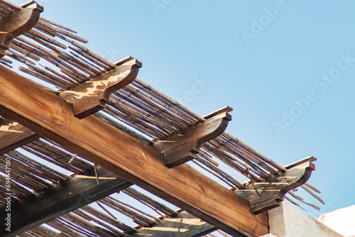 Vigas de madera de un alero en una casa de playa. Primer plano del detalle de la construcción con cañas. Las Negras, Almería, España.
