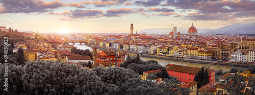 Florence (Firenze, Italy. Sunset panorama. Evening view at ancient city. Famous Ponte Vecchio bridge on river Arno scenic clouds and sky. Duomo Santa Maria del Fiore cathedral, Palazzo Tower