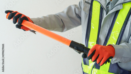 誘導棒を持つ作業服の男性｜建設業・警備員・ガードマン イメージ