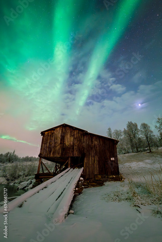 Stary drewniany budynek, na tle zorzy polarnej w Norwegii