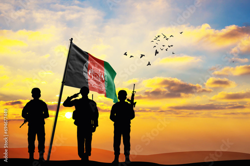 Silhouettes of soldiers with the Afghanistan flag stand against the background of a sunset or sunrise. Concept of national holidays. Commemoration Day.