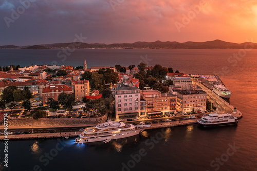 Zadar, Croatia - Aerial view of the Old Town of Zadar at dusk with mooring yachts, Cathedral of St. Anastasia and a dramatic golden summer sunset at background