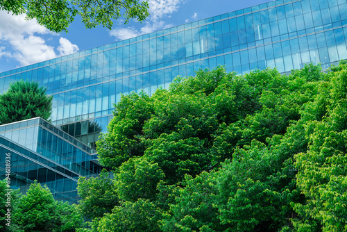 Eco-friendly building in modern city. Sustainable glass office building with trees for reducing CO2. Green architecture. Building with green environment. Sustainability corporate. Net zero emissions.