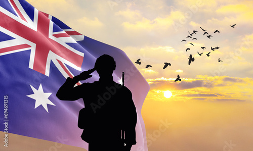 Silhouette of a soldier with the Australia flag stands against the background of a sunset or sunrise. Concept of national holidays. Commemoration Day.