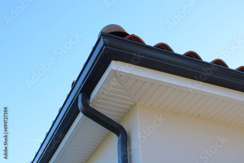 Gouttière aluminium gris anthracite sur la façade de la maison, descentes rectangulaires et lambris de sous-face