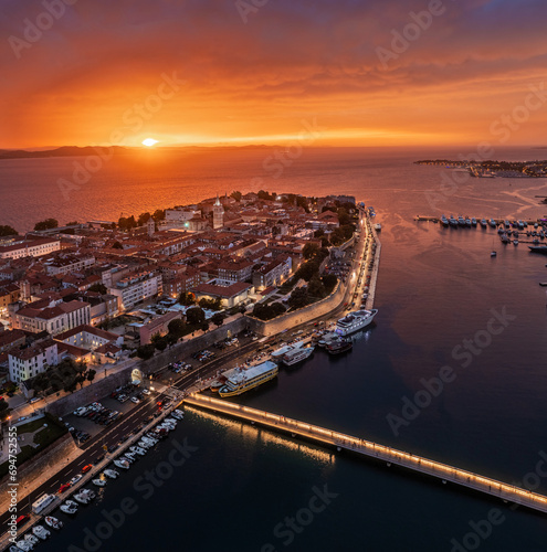 Zadar, Croatia - Aerial panoramic view of the old town of Zadar with colorful dramatic sunset sky, illuminated City Bridge (Gradski most), Cathedral of St. Anastasia tower and yacht marina