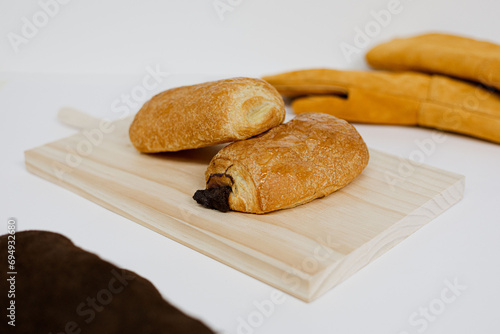 Napolitanas de chocolate y crema en una tabla de madera sobre fondo blanco. Fotografía de producto de panadería