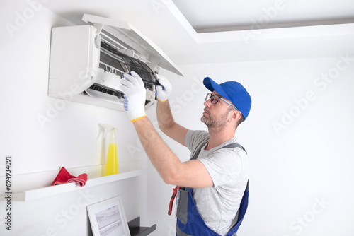 Service guy cleaning and maintaining air condition unit.