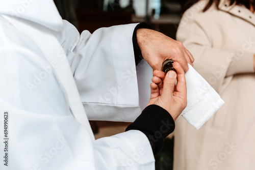 Un sacerdote impregnándose un dedo con un Santo Óleo durante una ceremonia de bautismo. Óleo de los Catecúmenos. Santo Crisma. Aceite sagrado en el catolicismo.