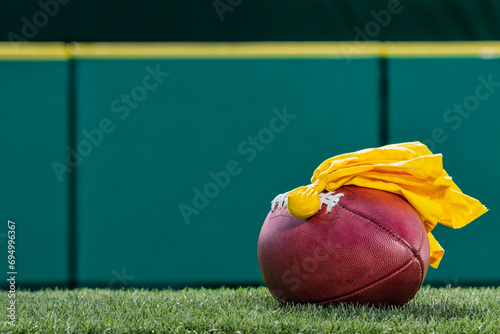 An American football with a yellow penalty flag sitting on top