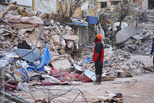 A rescue team is standing in front of a building site destroyed by a large earthquake to evacuate and search for victims trapped in the rubble.