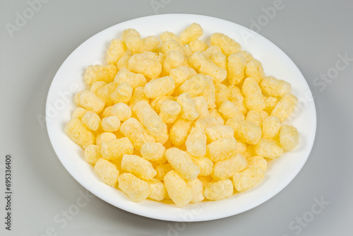 Sweet corn puffs on a white plate on gray background