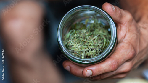 User of Medical Cannabis Marijuana Buds Showing a Glass With Some Samples of Hemp