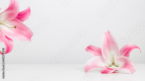 White table podium with lily pink flowers and copy space. Floral background for design, cosmetic, perfume and product presentation