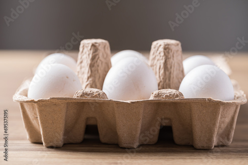 Organic white leghorn egg from free range farm in paper tray on wooden table