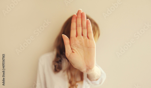 Upset young woman shows stop, no or enough sign with palm of hand, refusal gesture, domestic violence