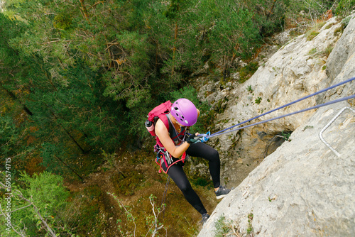 Woman initiating rappel with a forest background