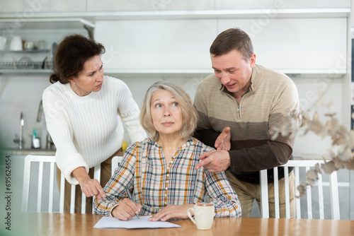 Middle-aged family members partitioning inheritance with mother sitting at kitchen-table with a sheet of paper and pen in hand