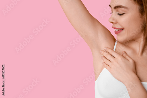 Beautiful young happy woman after epilation of armpit on pink background