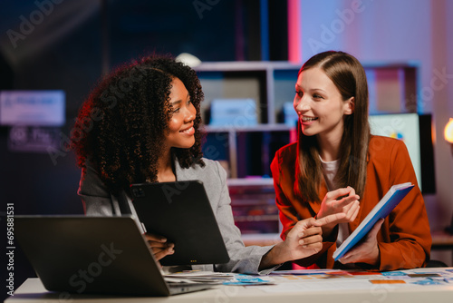 African American business worker with an afro presenting a UX,UI design on a clipboard to a Caucasian colleague in an office setting.