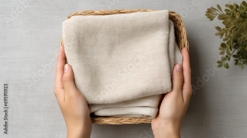Top view folded Linen towel inside basket with hands of person holding it, Natural cosmetic beauty spa or laundry concept
