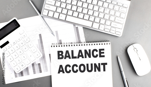 BALANCE ACCOUNT text on a notebook with chart and keyboard business concept