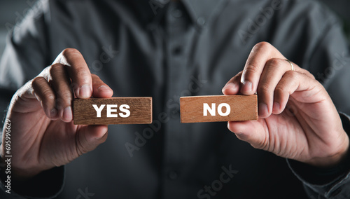Hands of businessman holding wooden blocks with yes and no words portraying decision-making. Choice symbolizes business success. Think With Yes Or No Choice.