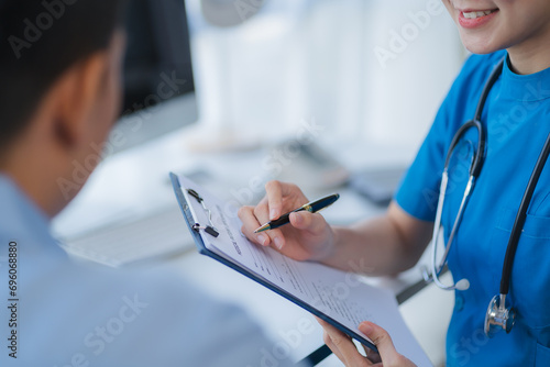 Doctor and patient sitting and talking at medical examination at hospital office, close-up. Therapist filling up medication history records. Medicine and