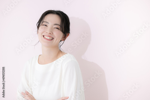 カメラ目線で白いカジュアルな服を着た笑顔の若い女性の上半身 ピンクの背景