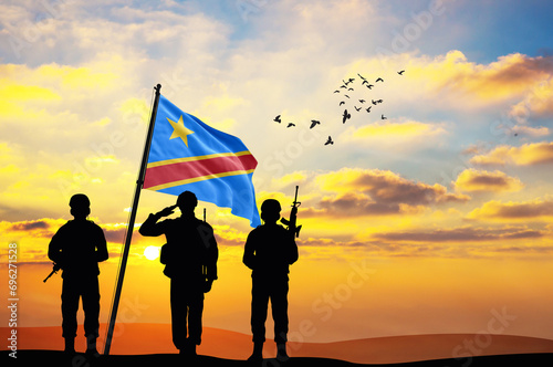 Silhouettes of soldiers with the DR Congo flag stand against the background of a sunset or sunrise. Concept of national holidays. Commemoration Day.