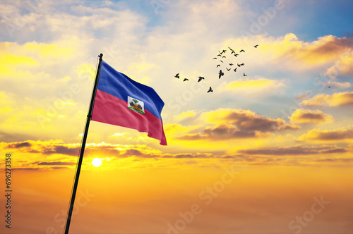 Waving flag of Haiti against the background of a sunset or sunrise. Haiti flag for Independence Day. The symbol of the state on wavy fabric.