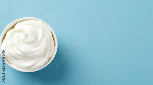 Bowl of white cream on blue background with copy space