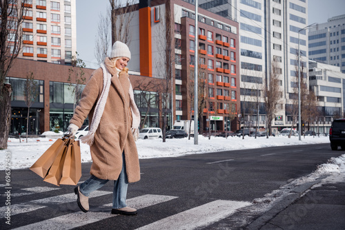 Photo of adorable pretty woman wear beige coat crossing road purchase new year presents outside urban city street