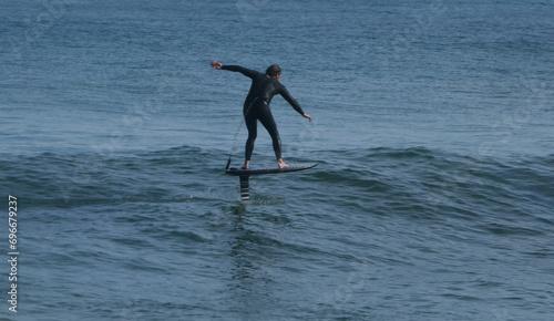 rear view of man wearing wetsuit surfing on hydrofoil board 