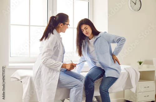 Pregnant woman feeling unwell suffering from backache during meeting with her gynecologist doctor in clinic. Female obstetrician consulting expectant girl sitting on the couch in office.