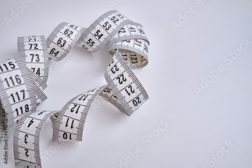 White measuring tape on a white background. Tool for measuring length and volume. Tape for measuring in the clothing industry or the volume of the human body