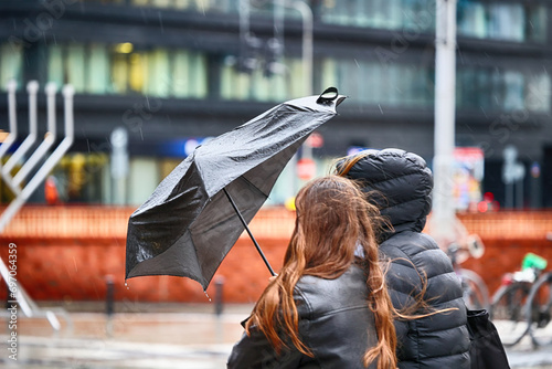 Ludzie pod parasolem w czasie deszczu i wiatru. 