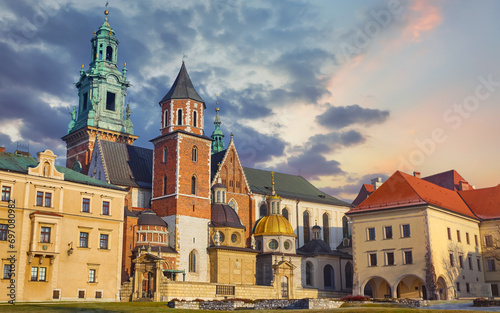Wawel castle in Krakow, Poland. Towers of Catholic temple. Picturesque territory and buildings architecture. Winter day with evening warm sunshine lighting. Sky dramatic clouds