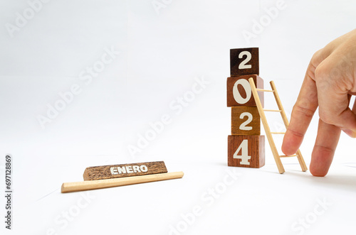 Dedos construyendo el año nuevo 2024 con escalera de madera. Proyección, ideas y propósitos para el mes de enero. Cubos de madera que forman verticalmente el número 2024 con fondo blanco. 