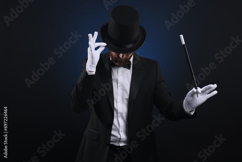 Magician in top hat holding wand on dark blue background