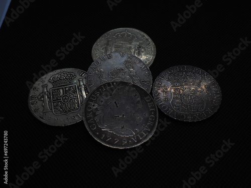 Spanish Escudo and Real coins in gold and silver on a black background